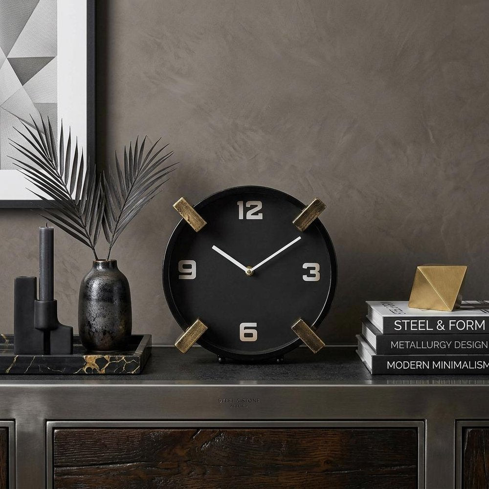 10" Black Stainless Steel Table Clock styled in a furnished interior with a brown wall on a black floor.