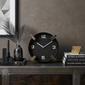 10" Black Stainless Steel Table Clock styled in a furnished interior with a brown wall on a black floor.