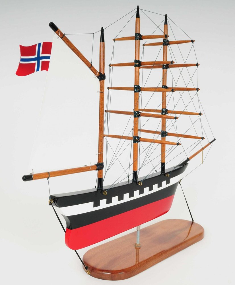 Wooden model ship with red, white, and black hull, multiple masts and rigging, and a Norwegian flag on a white background.