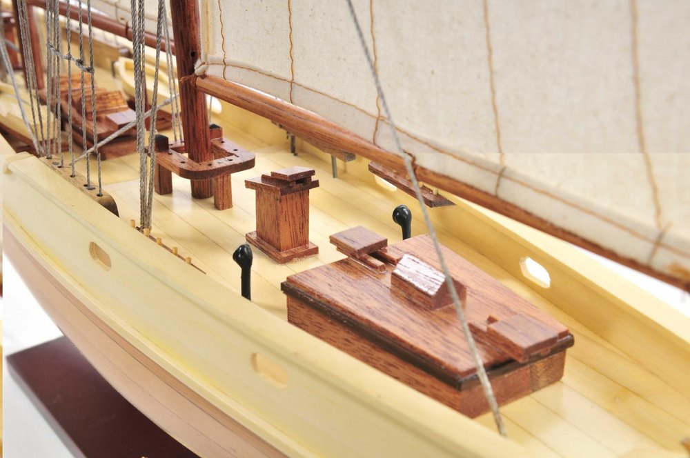24" Brown Solid Wood Hand Painted Model Boat styled in a furnished interior with a cream wall on the floor.