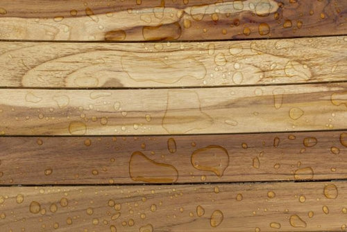 Brown teak shower bench with water droplets on a slatted surface.