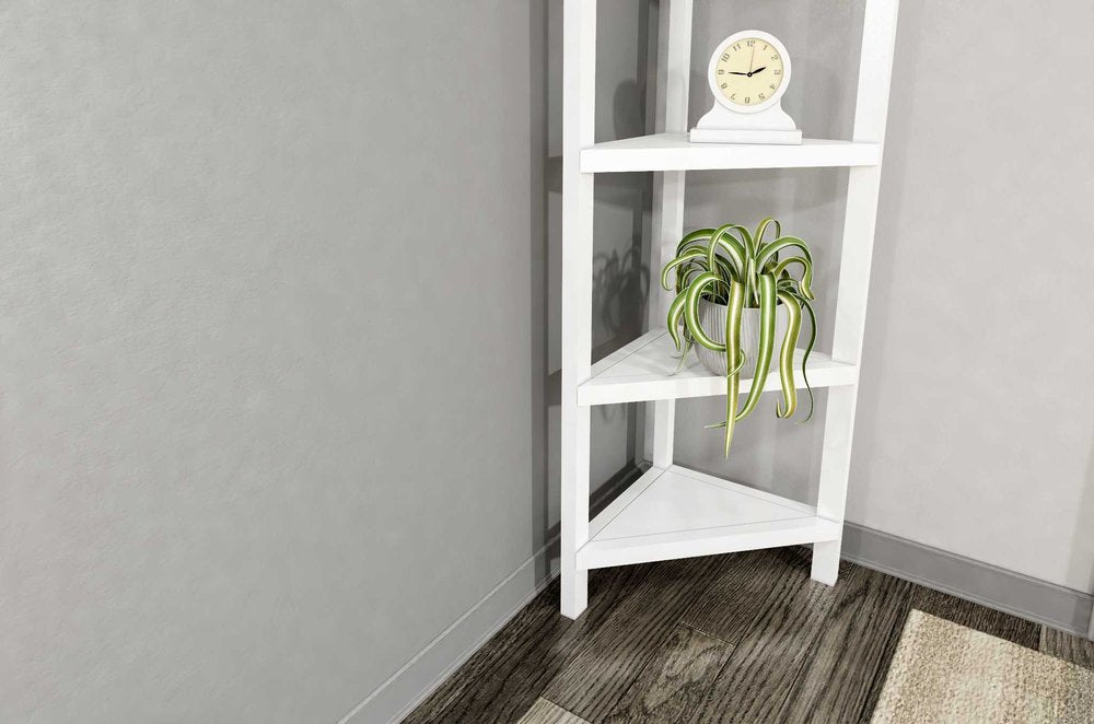 White solid wood corner bookcase with a plant and clock on shelves, set against a gray wall and dark wood floor.