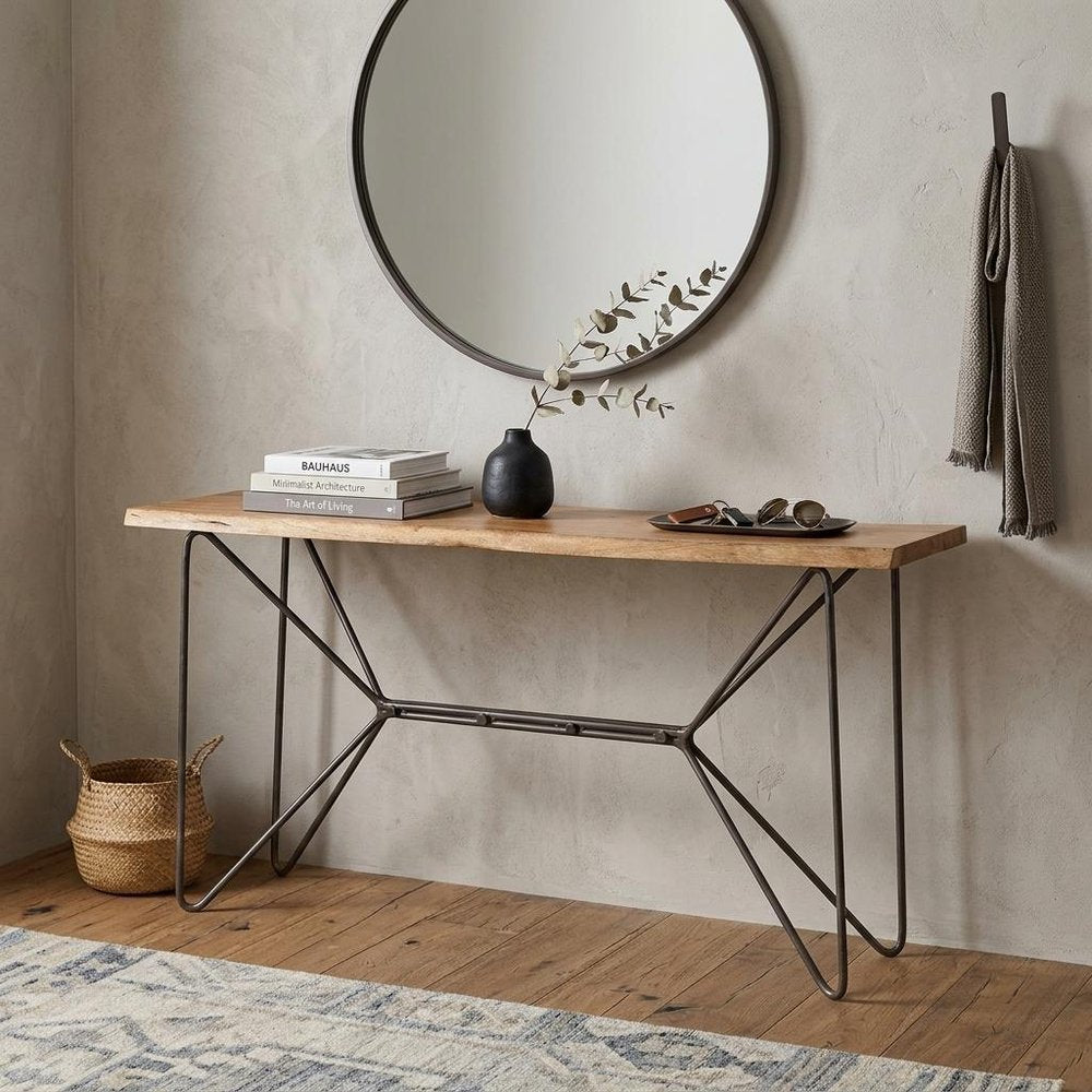 66" Brown and Black Solid Wood and Iron Abstract Base Console Table styled in a furnished interior with a light gray wall on a dark wood floor.