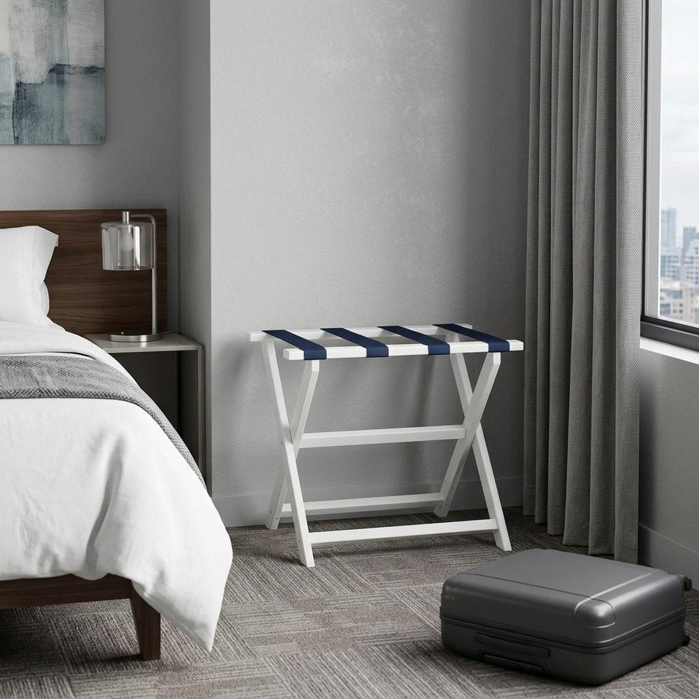 Earth Friendly White Folding Luggage Rack With Navy Straps in a home interior