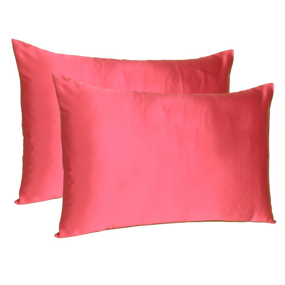 Two salmon pink silky satin pillowcases on a white background.