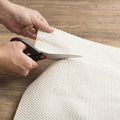 8' X 11' Beige Non Slip Rug Pad styled in a furnished interior with a tan wall on a off-white floor.