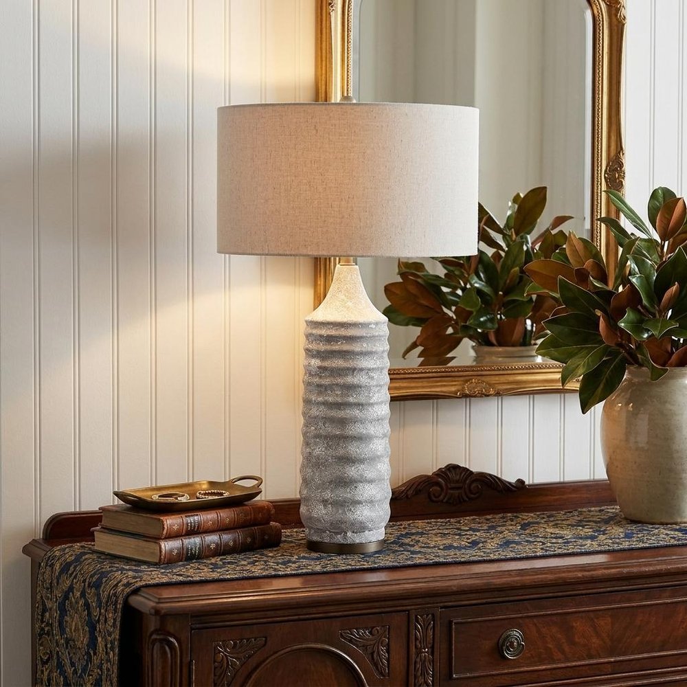 31" Gray Lamp Base LED With Beige Shade styled in a furnished interior with a tan wall on a dark wood floor.