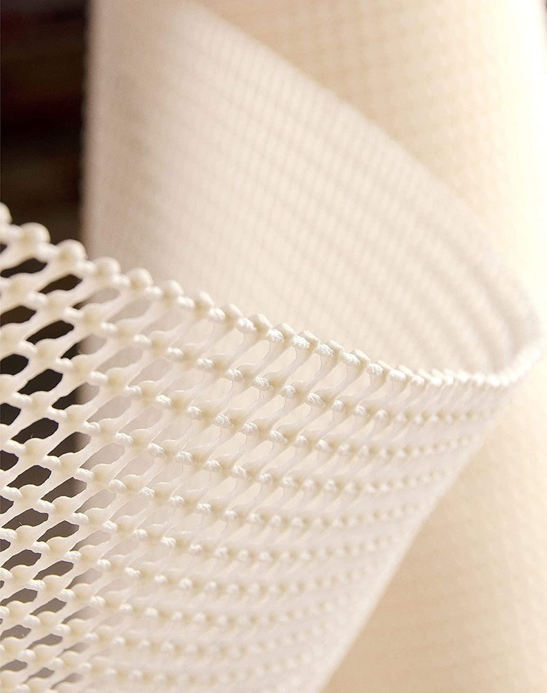 6' x 9' Ivory Striped Weave Non Slip Rug Pad styled in a furnished interior with a cream wall on the floor.