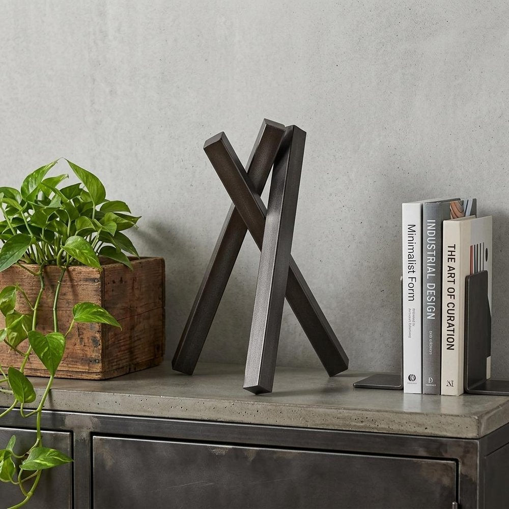 12" Gunmetal Gray Metal Abstract Geometric Tabletop Sculpture styled in a furnished interior with a light gray wall on a charcoal floor.