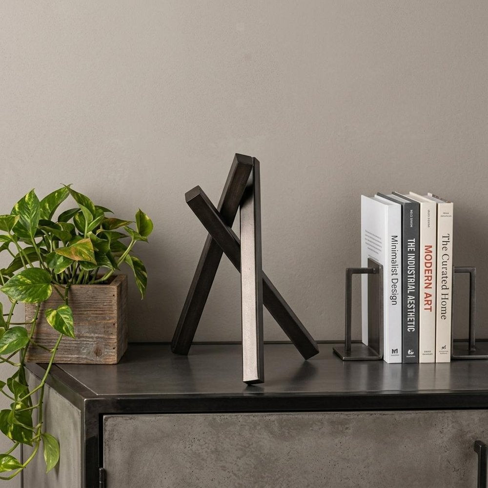 10" Black Metal Abstract Tabletop Sculpture styled in a furnished interior with a tan wall on a wood floor.