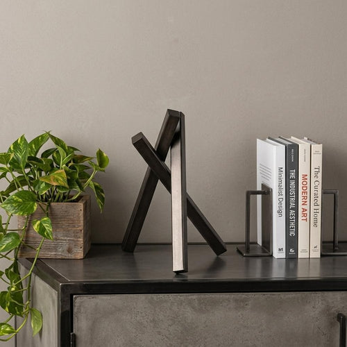 10" Black Metal Abstract Tabletop Sculpture styled in a furnished interior with a tan wall on a wood floor.