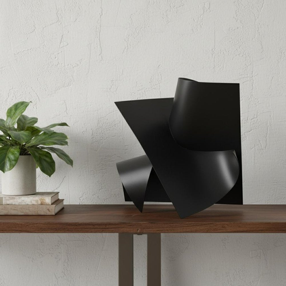 12" Contempo Antiqued Black Abstract Sculpture styled in a furnished interior with an off-white wall on a tiled floor.