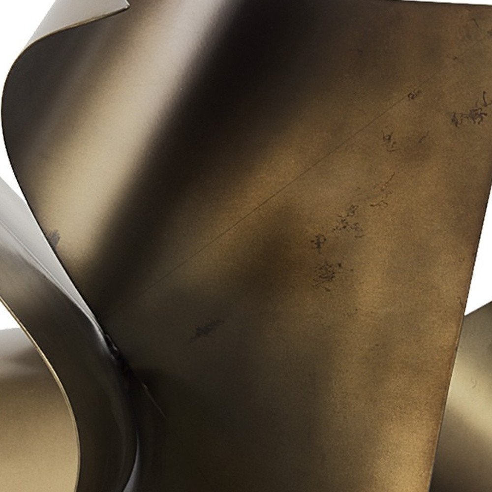 12" Contempo Antiqued Gold Abstract Sculpture styled in a furnished interior with a dark brown wall on a dark wood floor.