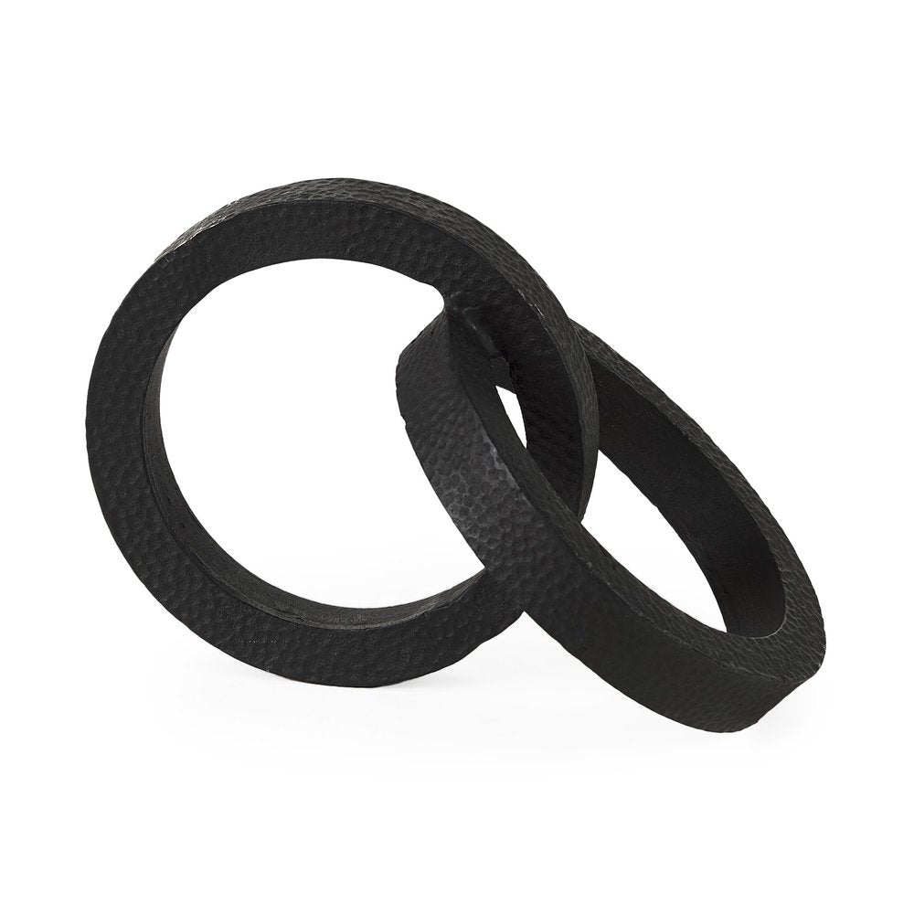 Black hammered metal sculpture of two interlocking rings on a white background.