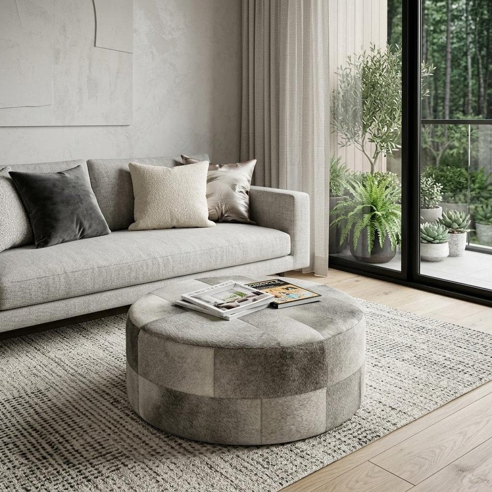 36" Gray Wool And Brown Footstool Ottoman styled in a furnished interior with a light gray wall on a dark wood floor.