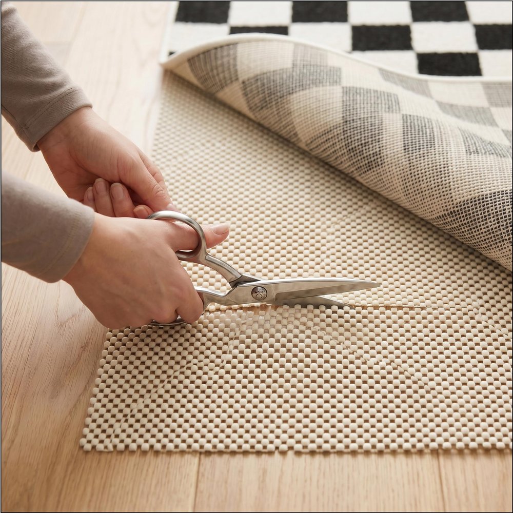 6' x 9' Ivory Striped Weave Non Slip Rug Pad styled in a furnished interior with an off-white wall on the floor.