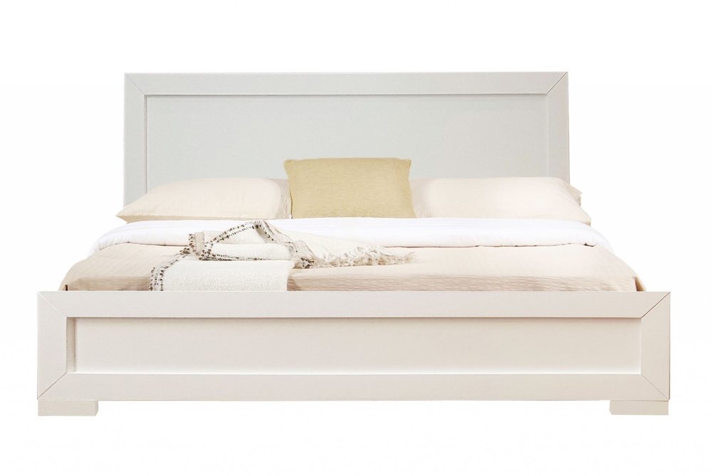 White solid and manufactured wood queen bed frame with pillows and blankets on a white background.
