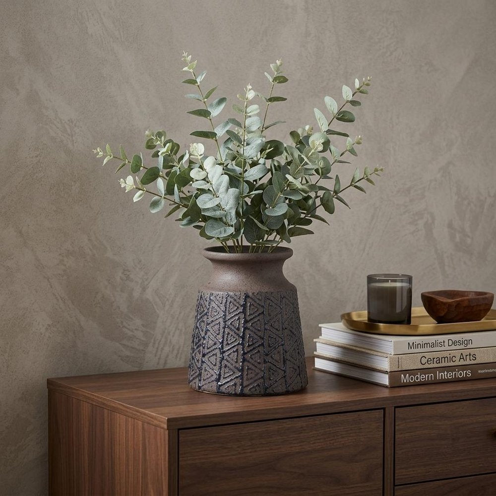 6" Brown Abstract Cylinder Ceramic Table Vase displayed on a dark wood tabletop in a furnished interior against a tan wall.