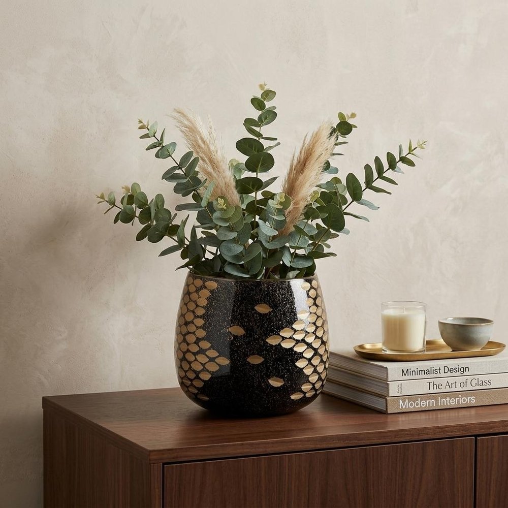 6" Gold Abstract Cylinder Crystal Glass Table Vase displayed on a dark wood tabletop in a furnished interior against a cream wall.