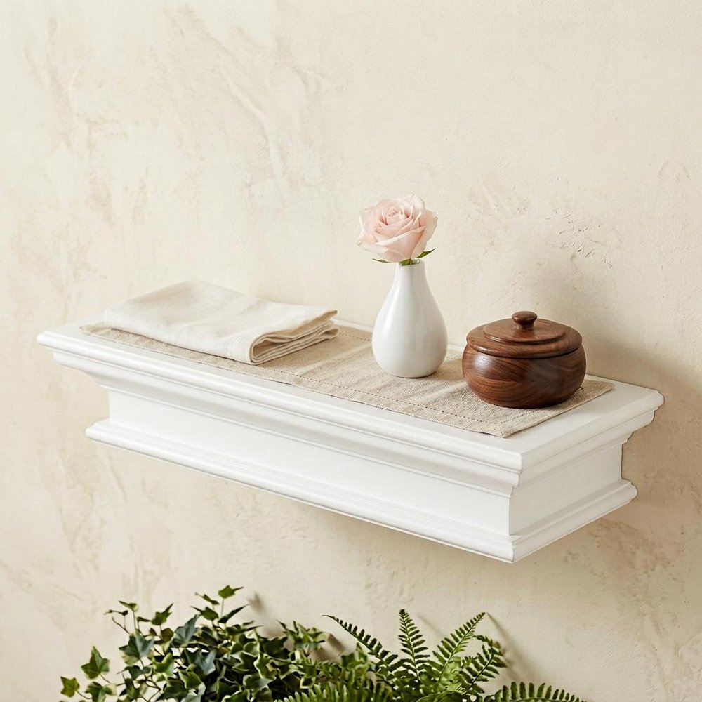 23" Classic White Floating Wall Shelf styled in a furnished interior with a cream wall on the floor.