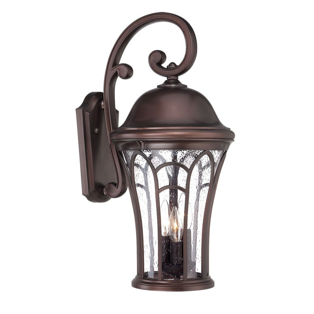 Bronze tapered goblet wall light with seeded glass panels and ornate scrollwork on a white background.