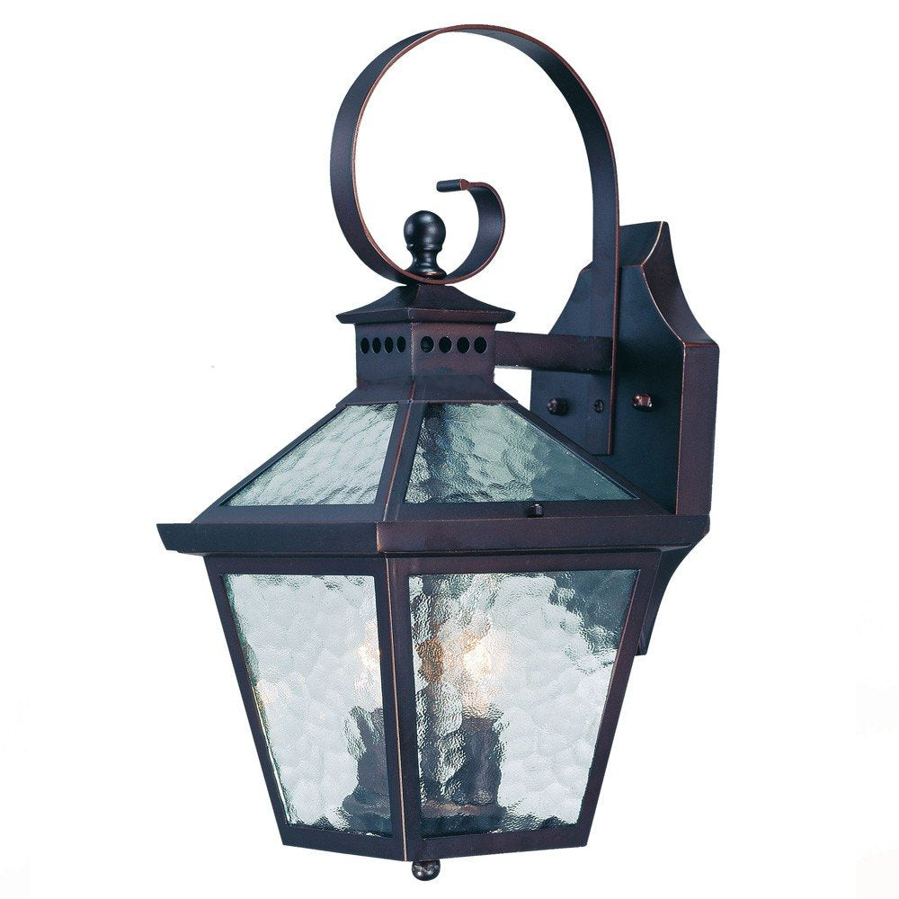 Antique bronze wall lantern with hammered glass panels and a decorative scroll arm, set against a white background.