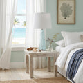 29" Aqua Glass Buffet Lamp With Off White Empire Shade styled in a furnished interior with a light gray wall on a wood floor in off-white glass.