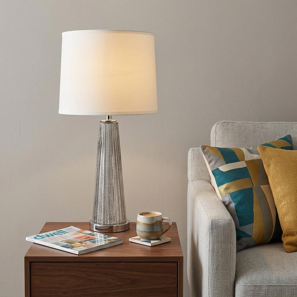 29" Silver Glass Buffet Lamp With Off White Empire Shade styled in a furnished interior with a tan wall on a dark wood floor in off-white glass.