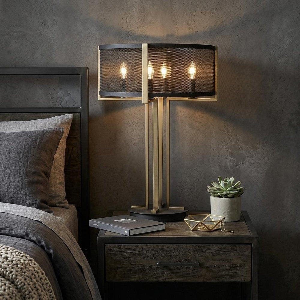 25" Brass Metal Four Light Geometric Table Lamp With Black Drum Shade displayed on a tabletop in a furnished interior against a dark wall.