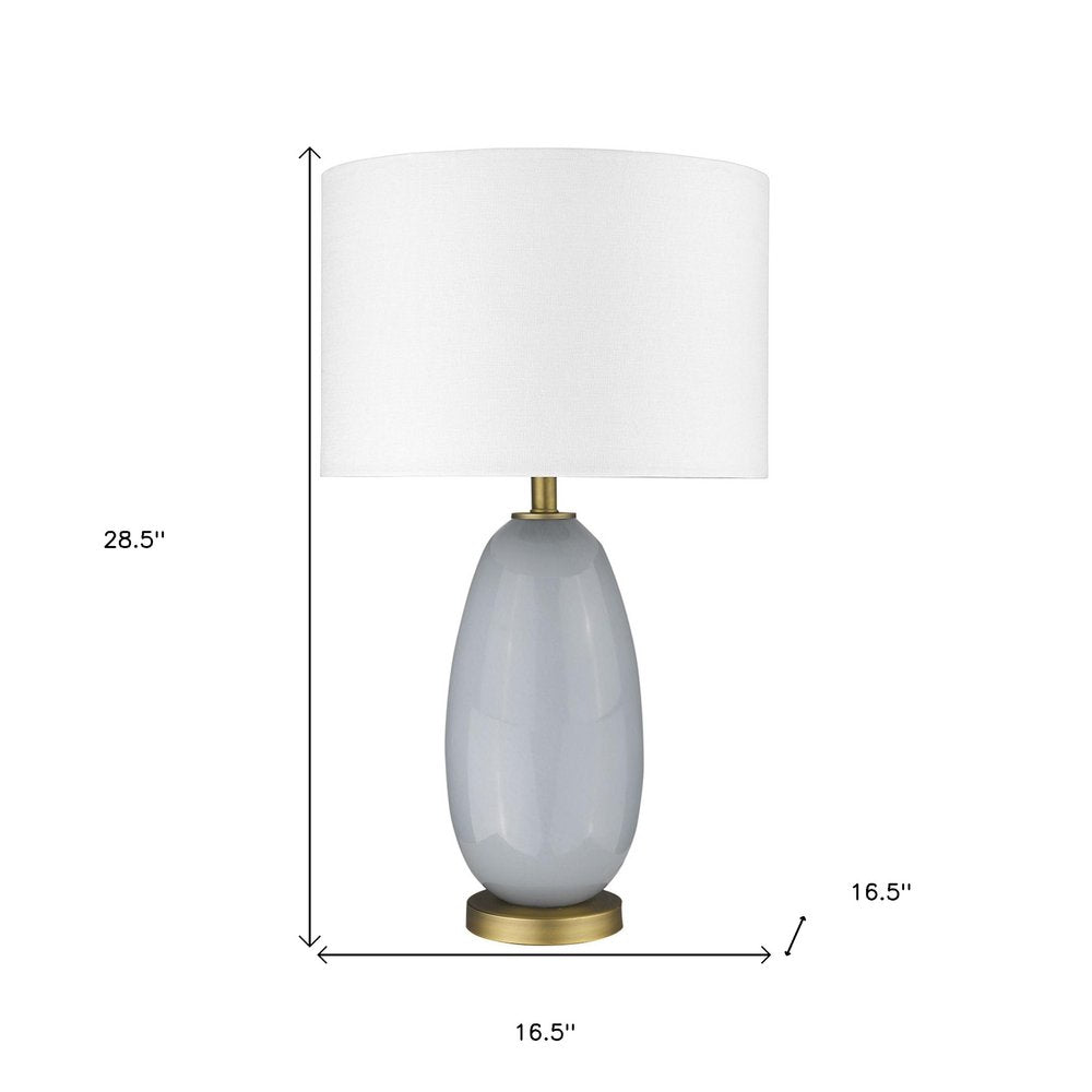 29" Light Gray Glass Table Lamp With White Drum Shade. Table lamp isolated on a plain white background, showing a light gray glass surface.