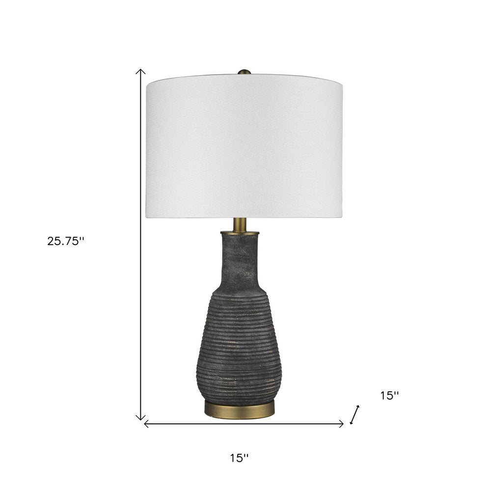 26" Distressed Black and Gold Ceramic Table Lamp With White Drum Shade. Table lamp isolated on a plain white background, showing a black ceramic surface.