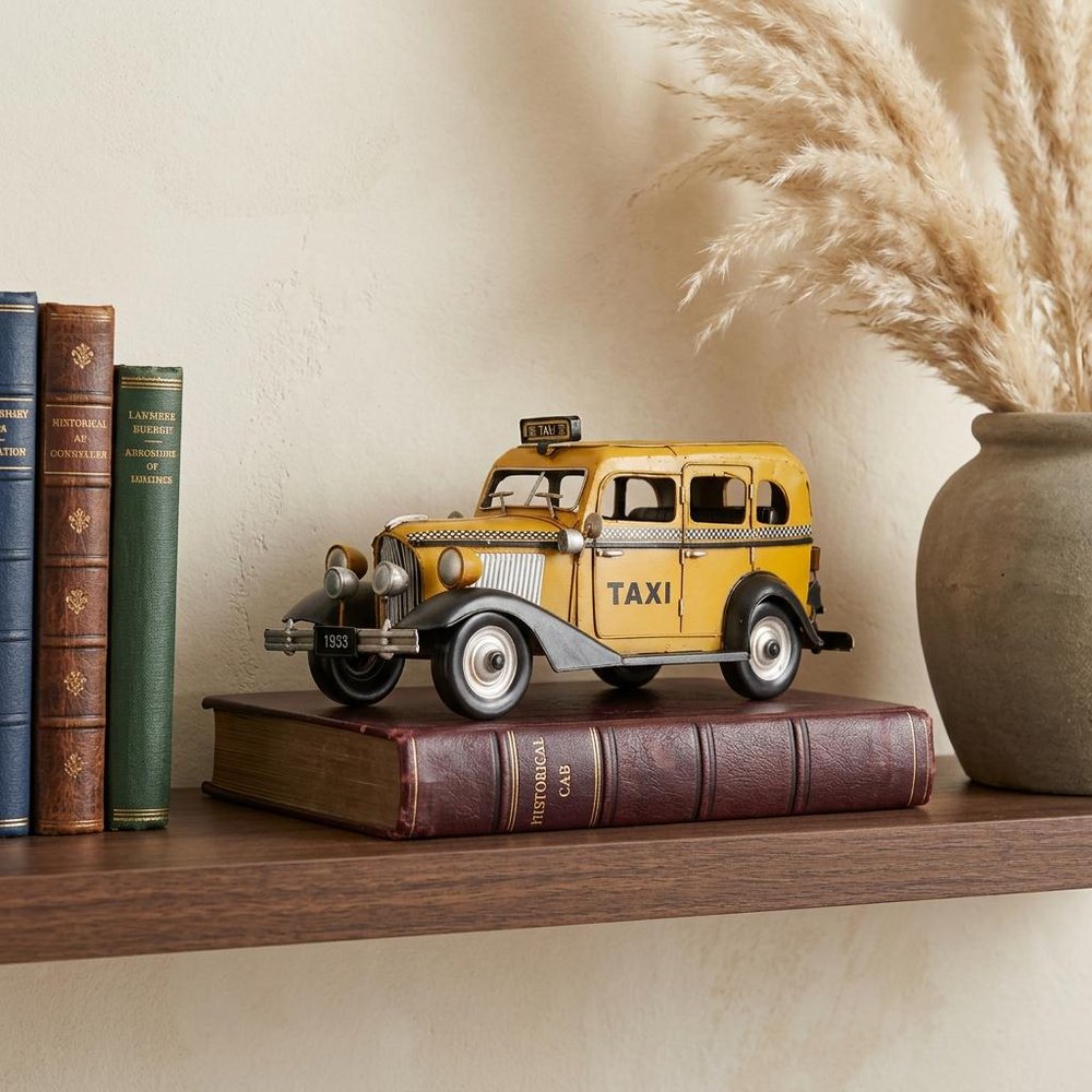 14" Yellow Checker Taxi Cab Model Sculpture styled in a furnished interior with a cream wall on a wood floor.