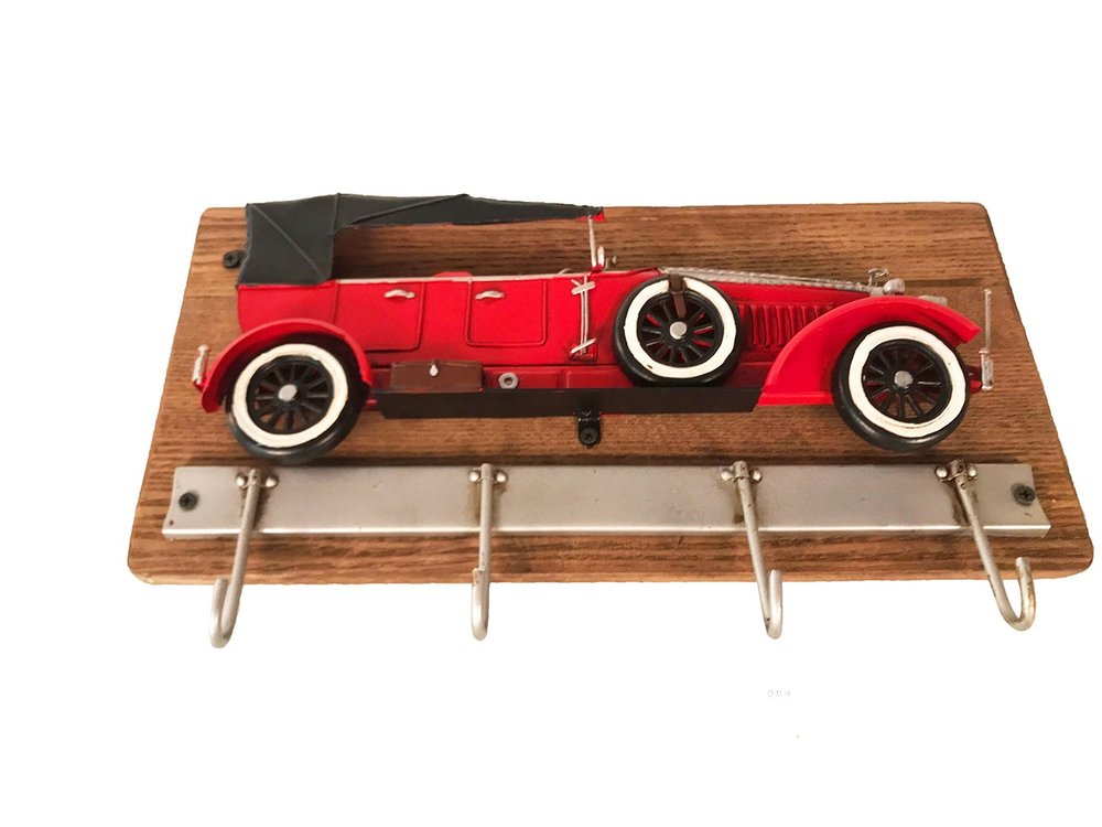 Red vintage car model on a wooden coat rack with four hooks against a white background.