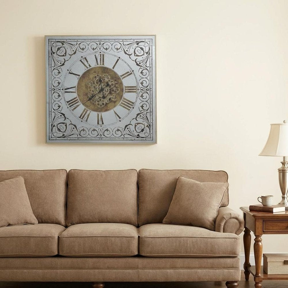 32" Gold And Silver Metal Analog Distressed Square Wall Clock styled in a furnished interior with an off-white wall on a dark wood floor.