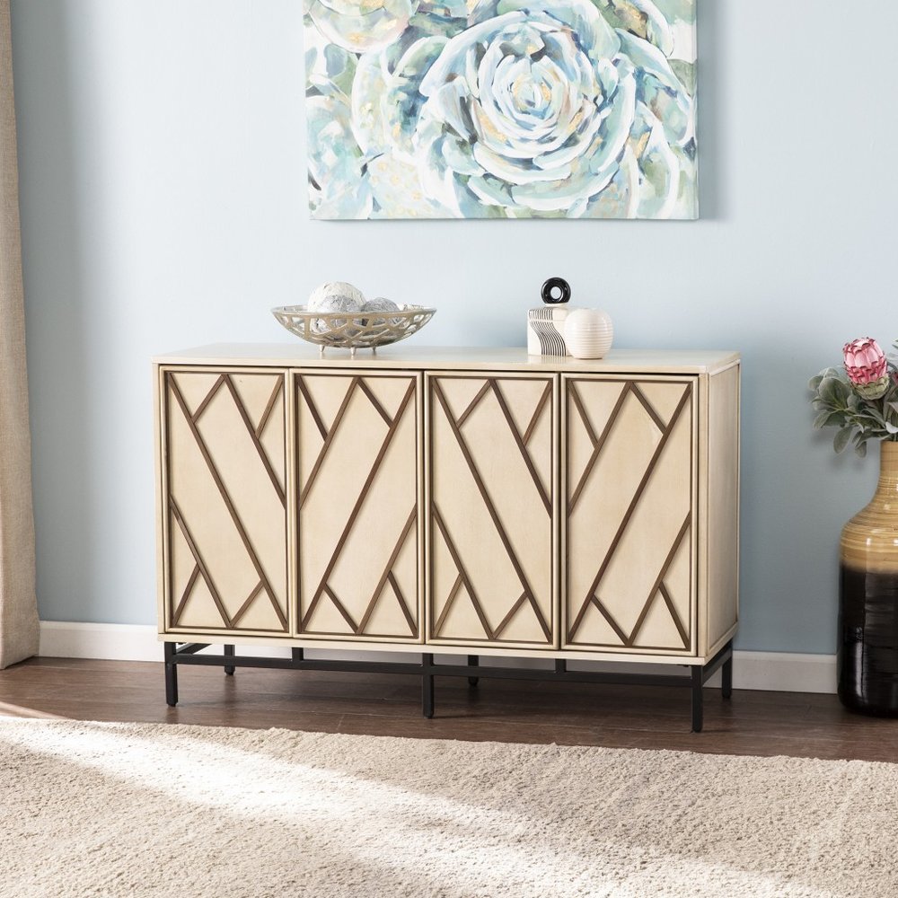 Champagne deco buffet storage cabinet with geometric wood inlay on doors, set against a light blue wall with abstract art and a vase.