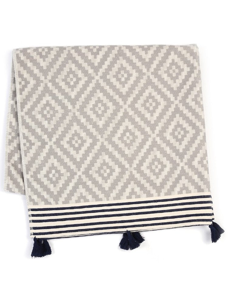 Gray and cream diamond pattern Turkish towel with navy and cream stripes and navy tassels on a white background.