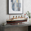 14" Black And Red Solid Wood Hand Painted Boat Model Boat styled in a furnished interior with a light gray wall on a charcoal floor.