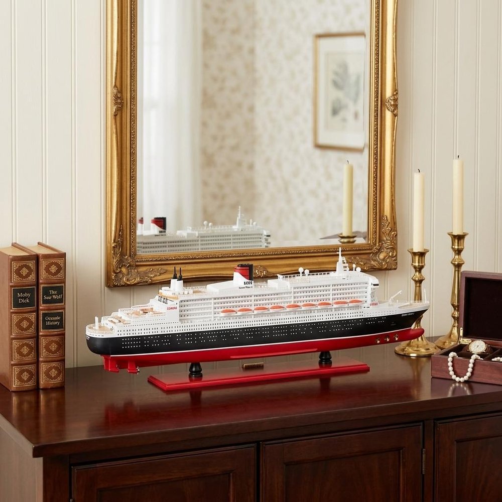 13" Black and Red RMS Queen Mary II Large Boat Hand Painted Decorative Boat styled in a furnished interior with a cream wall on a black floor.
