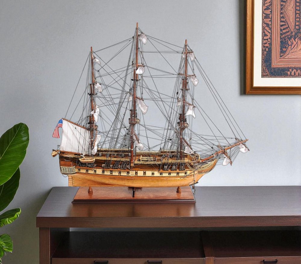 32" Brown Solid Wood Hand Painted Boat Model Boat styled in a furnished interior with a light gray wall on a black floor.