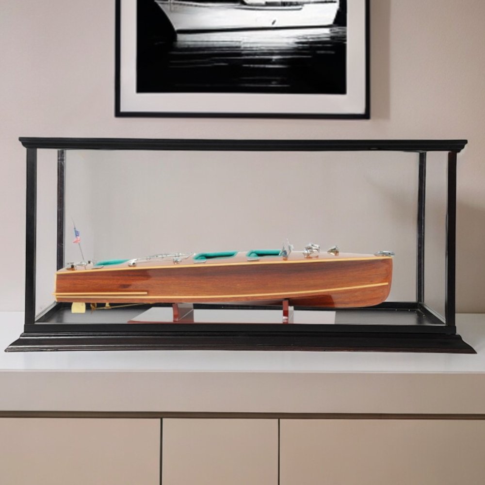 15" Wood Brown c1928 Chris Craft Triple Cockpit Hand Painted Boat with Case styled in a furnished interior with a light gray wall on a wood floor.