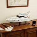 19" White Solid Wood Hand Painted Model Boat styled in a furnished interior with a cream wall on a dark wood floor.