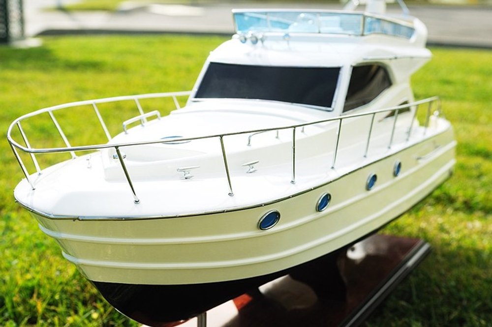 19" White Solid Wood Hand Painted Model Boat shown outdoors on an outdoor setting with greenery.
