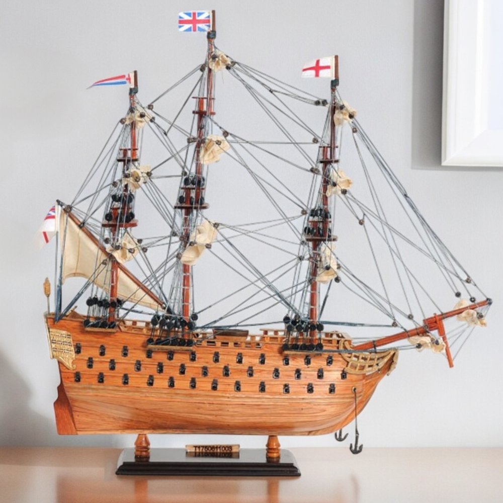 18" Wood Brown HMS Victory Hand Painted Decorative Boat styled in a furnished interior with an off-white wall on a off-white floor.