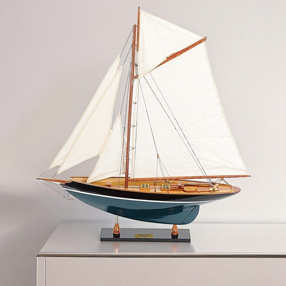 31" Black Blue And White Solid Wood Pen Duick Hand Painted Model Sail Boat styled in a furnished interior with an off-white wall on a blush floor.