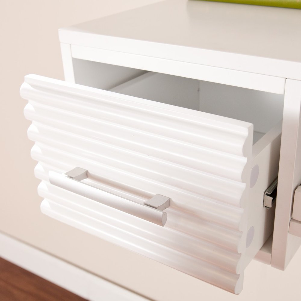 White wall-mounted desk with a fluted drawer front and silver handle, against a neutral wall.