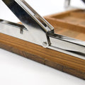 Close-up of a shiny metal hinge attached to a brown teak wood shower bench, showing the product's material and construction.