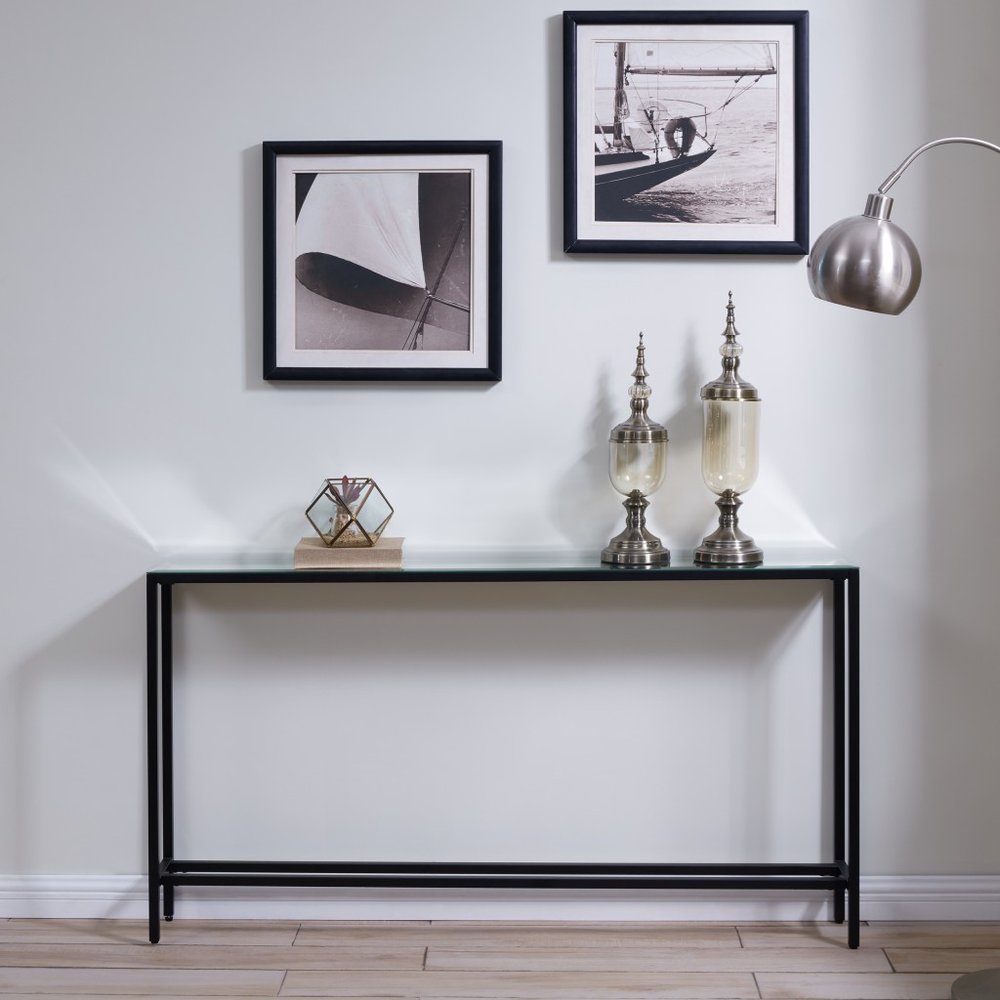 Black metal console table with a mirrored glass top, featuring two decorative glass urns and a geometric terrarium.