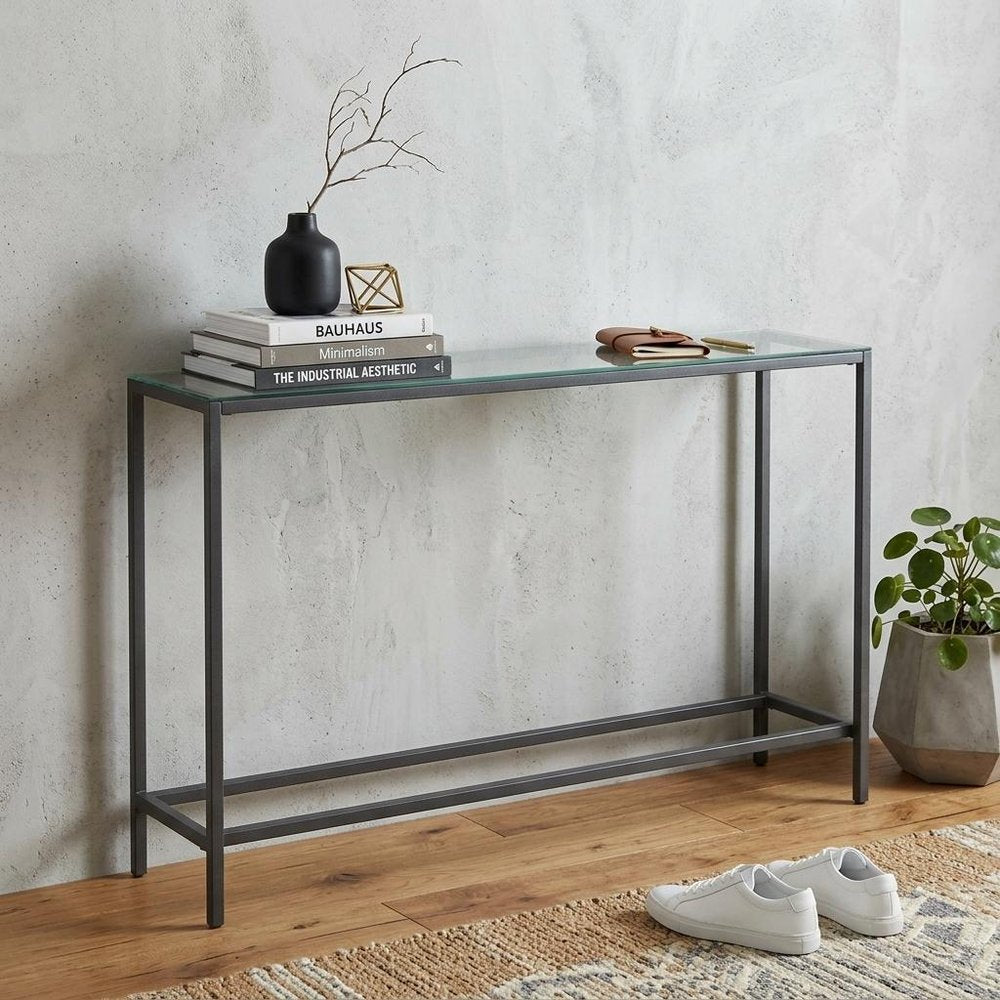 56" Silver and Gunmetal Mirrored Glass and Metal Console Table styled in a furnished interior with an off-white wall on a wood floor.