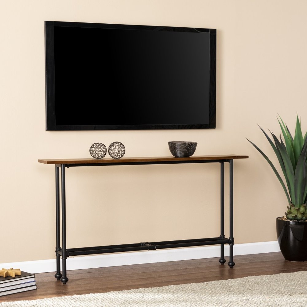Espresso and black metal console table with a wooden top against a beige wall with a large TV above.