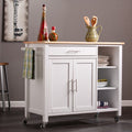 42" Natural and White Butcher Block and Iron Rolling Kitchen Cart With Storage styled in a furnished interior with a brown wall on a charcoal floor in tan metal.